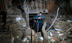 Un habitant de Kharkiv retire un vélo d'un immeuble endommagé par une frappe russe, le 30 décembre 2023