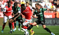 L'attaquant de Reims Folarin Balogun (c) tente un passage au milieu des Lensois Kavin Danso (g) et Jonathan Gradit (d), le 4 septembre 2022 à Reims   