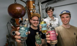 (g-d) Les frères Gyger, Gaetan, Luca et Tim, montrent des bouteilles de gin et de gentiane devant l'alambique de leur distillerie Gagygnole de Souboz, le 10 mai 2022 en Suisse