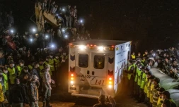 Les forces de sécurité contiennent la foule pour laisser passer l'ambulance transportant le corps du petit Rayan, retrouvé mort cinq jours après être accidentellement tombé dans un puits à Ighrane, le 5 février 2022 dans le nord du Maroc
