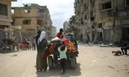 Des Palestiniens transportent leurs affaires sur un chariot entre des bâtiments détruits à Khan Younès, dans le sud de la bande de Gaza, le 2 mai 2024