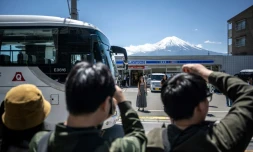 Des touristes photographient le mont Fuji avant l'installation d'un vaste filet pour cacher la vue, le 3 mai 2024 à Fujikawaguchiko, au Japon