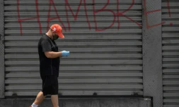 Un homme, protĂ©gĂ© par un masque contre le coronavirus, passe devant un rideau de fer oĂč est Ă©crit "Faim", Ă Caracas, le 14 mai 2020