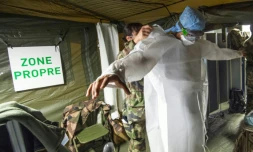 Une militaire aide un collègue à enfiler une blouse de protection sans la contaminer, le 24 mars 2020 à l'hôpital de campagne destiné à accueillir les malades du Covid-19, à Mulhouse