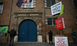 Un homme brandit une pancarte lors d’une manifestation contre le projet d’autoroute A69, devant la cour administrative d’appel à Toulouse, le 11 décembre 2025