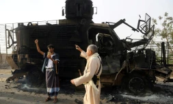 Des hommes armés yéménites inspectent un véhicule détruit après des affrontements entre forces loyalistes et rebelles près du port de Hodeida (ouest), cible d'une offensive du pouvoir aidé par l'Arabie saoudite et les Emirats, le 29 mai 2018