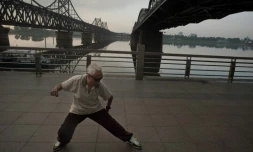 Un homme fait du Tai Chi au lever du soleil le 5 juillet 2017 à Dandong, près du Pont de l'Amitié reliant la Chine à la Corée du Nord