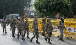 Les membres des forces de sécurité arrivent pour prendre leur poste à un point de contrôle temporaire à New Delhi, le 11 octobre 2026
