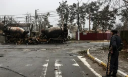 Un homme regarde des camions brûlés dans une rue d'Irpin, prÚs de Kiev, le 1er avril 2022