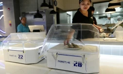 Une employée du restaurant Robot.He dépose un plat sur le robot serveur, le 30 juillet 2018 à Shanghai, en Chine