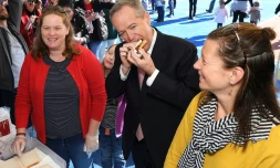 Bill Shorten (c), le dirigeant travailliste donné favori pour devenir le nouveau Premier ministre d'Australie, déguste une saucisse aprÚs avoir voté aux élections législatives à Melbourne, le 18 mai 2019