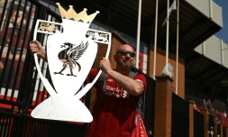 Un supporter de Liverpool pose avec un trophée factice aprÚs le sacre de Liverpool champion de Premier League, le 26 juin 2020
