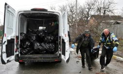 Des employĂ©s municipaux chargent un corps dans une camionette le 3 avril 2022 Ă Boutcha, ville au nord-ouest de Kiev oĂč les autoritĂ©s ukrainiennes accusent les forces russes d'avoir commis un massacre
