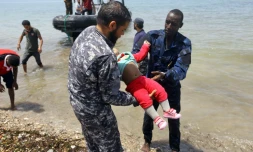 Des membres de la sécurité libyenne portent le corps d'un bébé dans la ville d'al-Hmidiya, après le naufrage au large de la Libye d'une embarcation de migrants dont 100 sont toujours portés disparus, le 29 juin 2018 