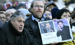 Des fans avec des portraits du chanteur "Merci Johnny" attendent devant l'Eglise de la Madeleine, le 9 décembre 2017 