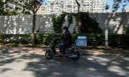 Zhuang Zhenhua, livreur, parcourt les rues de Pékin téléphone au volant de son scooter, le 7 septembre 2021