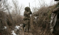 Un militaire ukrainien scrute les positions ennemies depuis une tranchée, près d'Avdiivka, dans le sud-est de l'Ukraine, le 9 janvier 2022