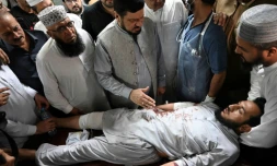 Le gouverneur de la province de Khyber Pakhtunkhwa, Haji Ghulam Ali (centre), réconforte un homme blessé lors de l'attentat suicide contre un meeting politique, le 30 juillet 2023 dans un hÎpital de Peshawar (Pakistan)