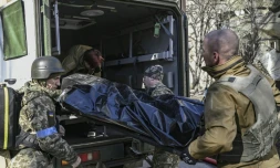 Des militaires ukrainiens évacuent le corps d'un soldat après une frappe russe, à Kiev, le 22 mars 2022