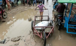 Une enfant pousse un chariot avec un sac de riz le 21 mai 2021, lors d'une distribution du PAM dans une banlieue de Rangoun