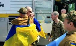 Photo prise et diffusée par le service de presse présidentiel ukrainien, le 9 juin 2025, de prisonniers de guerre ukrainiens enveloppés de drapeaux nationaux après un échange dans un lieu non divulgué