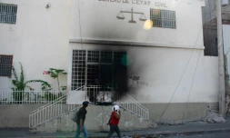 Des habitants passent devant le tribunal de Port-au-Prince incendié par des bandes armées, le 6 mars 2024 en Haïti