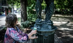 Une femme remplit un gobelet d'eau à une fontaine publique du quartier Montparnasse à Paris, le 25 mai 2026, alors que Météo-France a placé la capitale en alerte jaune face à une vague de chaleur exceptionnellement précoce