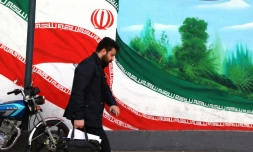 Une Iranien marche prÚs d'une fresque représentant le drapeau national, à Téhéran le 22 février 2026