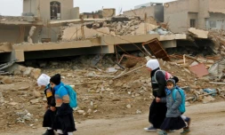 Des enfants irakiens marchent dans un quartier en ruines à Fallouja, en Irak, le 29 décembre 2016