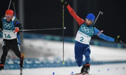 Le biathlète Martin Fourcade (d) franchit en vainqueur, au sprint et d'une courte spatule, la ligne d'arrivée de la mass start aux JO, le 18 février 2018 à Pyeongchang