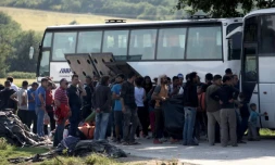 Des migrants montent à bord d'un bus le 23 mars 2016 à Idomeni