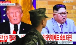 Un soldat sud-coréen passe devant un écran de télévision montrant des photographies du président américain Donald Trump (G) et du dirigeant nord-coréen Kim Jong Un dans une gare de Séoul, le 9 mars 2018