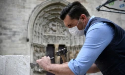 Un tailleur de pierre montre les gestes médievaux devant des visiteurs dans le cadre d'un atelier et du projet de reconstruction de la flÚche de la basilique Saint-Denis, devant l'édifice à Saint-Denis, le 5 juin 2020