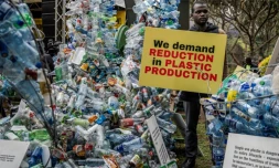 Un militant pour le climat tient une banderole à cÎté d'une installation de déchets en plastique, le 11 novembre 2023 à Nairobi, au Kenya, avant une réunion de 175 pays pour négocier des mesures concrÚtes pour lutter contre la pollution plastique