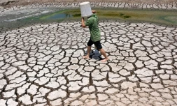 Un homme transporte un seau en plastique sur un étang asséché dans la province méridionale de Ben Tre, au Vietnam, le 19 mars 2024