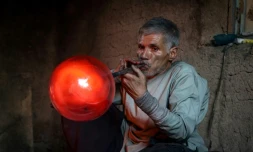 Ghulam Sakhi Saifi souffle du verre en fusion dans son atelier, le 11 août 2024 à Hérat, en Afghanistan
