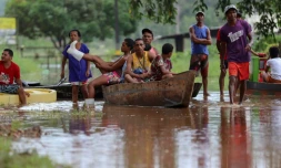 Des habitants utilisent une barque pour traverser un zone inondée dans le quartier Joaia do Atlantico, à Ilheus, dans le sud de l'Etat  brésilien de Bahia