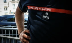 Un pompier avec "en grève" scratché sur la poitrine, devant  l'hôtel de Beauvau, à Paris, le 13 août 2026