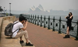 Des touristes portent des masques en raison des fumées toxiques liées aux incendies de forêts, le 10 décembre 2019 à Sydney, en Australie