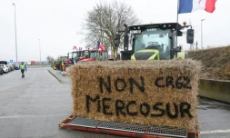 Une botte de foin "Non au Mercosur" sur un tracteur alors que des agriculteurs participent à un blocage sur l'autoroute A1 près de Fresnes-lès-Montauban, le 12 janvier 2026 dans le Pas-de-Calais