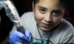 Brandon Burgos, 11 ans, réalise un tatouage sur un client, le 10 novembre 2021 à Puebla, au Mexique