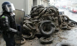 Un policier devant des pneus brûlés par des agriculteurs qui manifestent contre la baisse des prix de leurs produits à Saint-LÎ, le 2 février 2016-