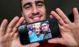 Anas Modami, réfugié Syrien, montre le selfie qu'il a pris avec Angela Merkel en septembre 2015, le 1er septembre 2021 dans son appartement de Berlin
