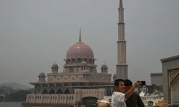 Deux personnes se prennent en photo devant une mosquée dans un air saturé par des fumées toxiques, à Putrajaya, en Malaisie, le 17 octobre 2026
