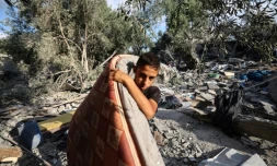 Un garçon palestinien récupère un matelas des décombres d'une maison après une frappe israélienne nocturne qui a touché Nousseirat, dans le centre de la bande de Gaza, le 13 juillet 2025