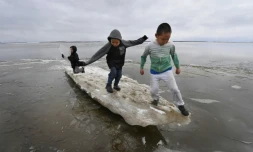 Des enfants jouent sur un bloc de glace en train de fondre dans le village eskimo yupik de Napakiak, le 18 avril 2019 en Alaska