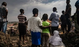 Des habitants assistent aux recherches des secours après l'effondrement d'une décharge à Kampala, le 10 août 2024 