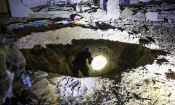 Des policiers et militaires israéliens inspectent un cratÚre causé par un missile iranien dans une école de Gedera, dans le sud d'Israël, le 1er octobre 2024