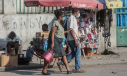 Des personnes portent un masque de protection contre le coronavirus dans une rue de Port-au-Prince, le 26 mars 2020 Ă HaĂŻti