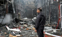 Un homme observe les dégâts alors qu'un pompier ukrainien éteint un incendie au marché "Barabashovo" après une attaque de drone à Kharkiv, le 6 mai 2025 en Ukraine